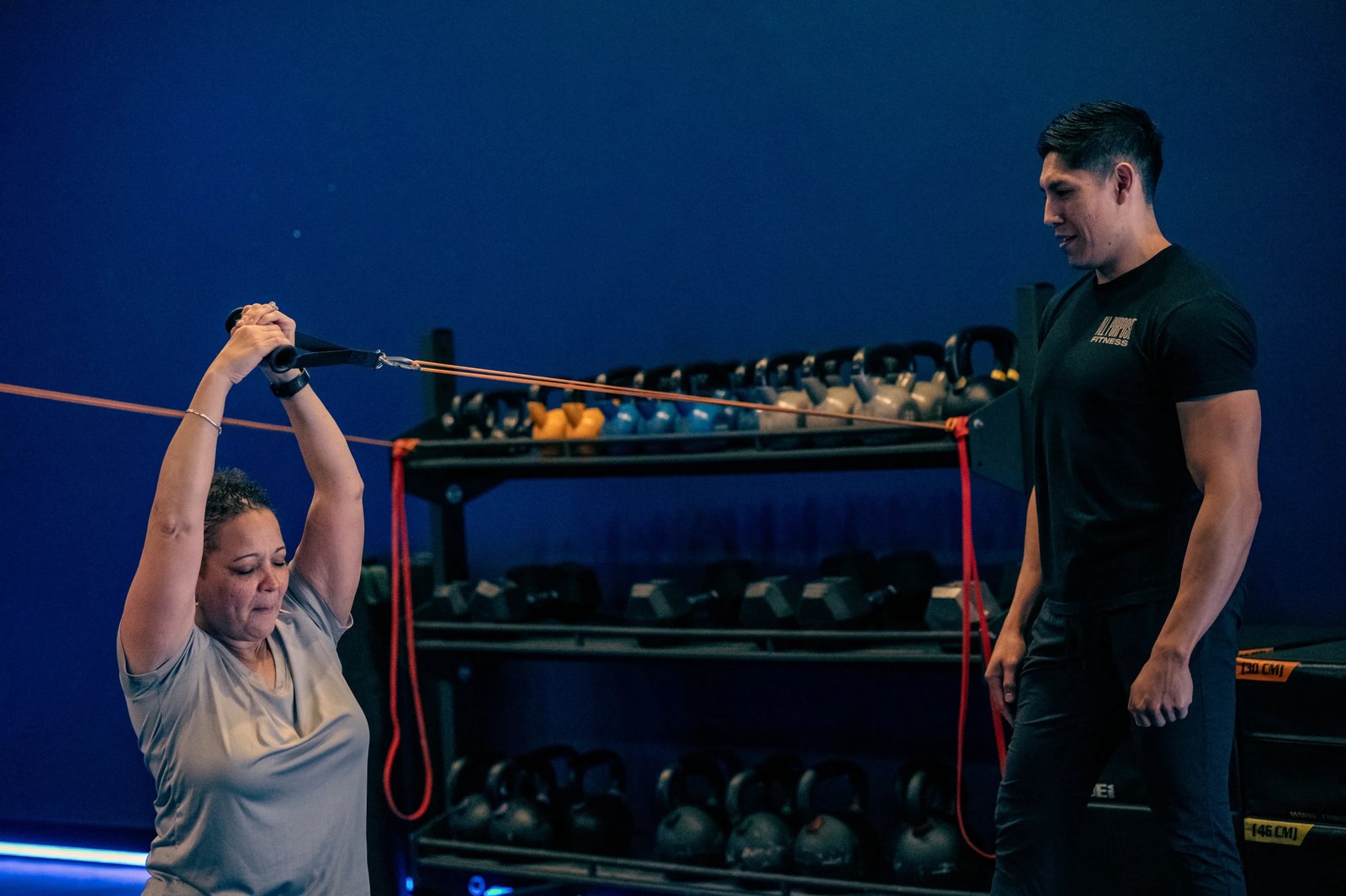 Coach watching two members do resistance band exercises