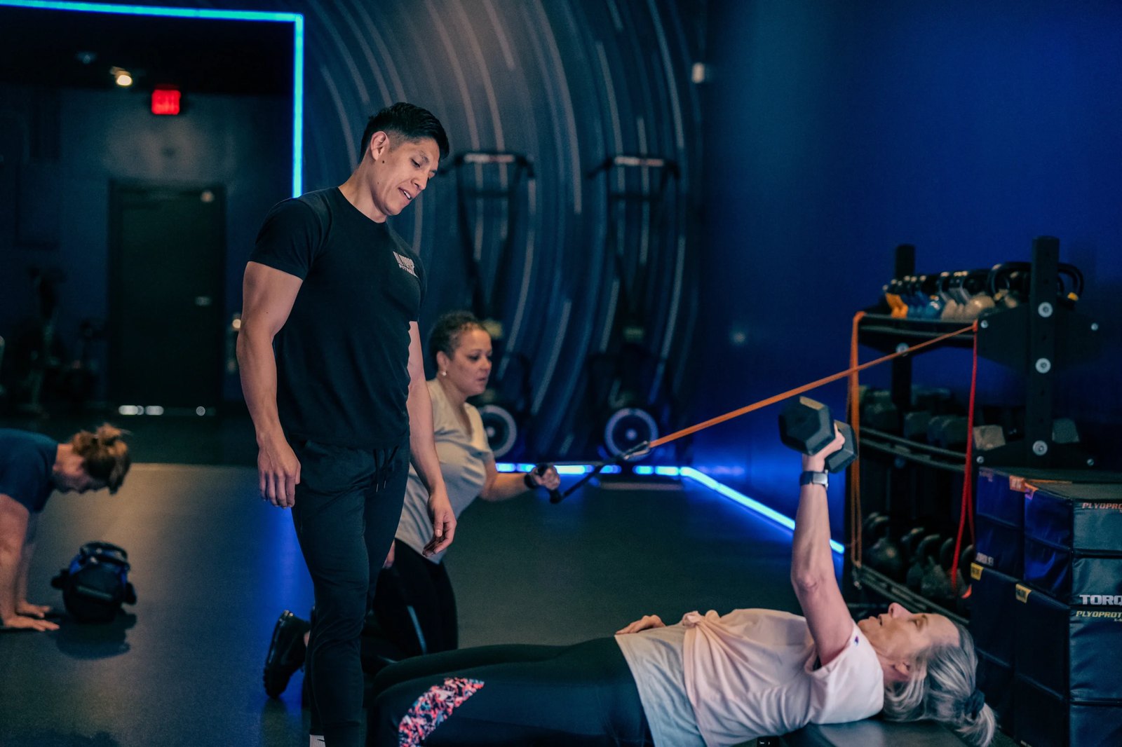 Coach demonstrating a bench exercise for an older member